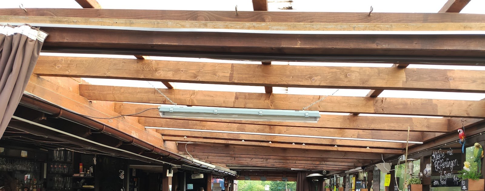 Das Holzbalkendach über dem Biergarten, links die Außentheke