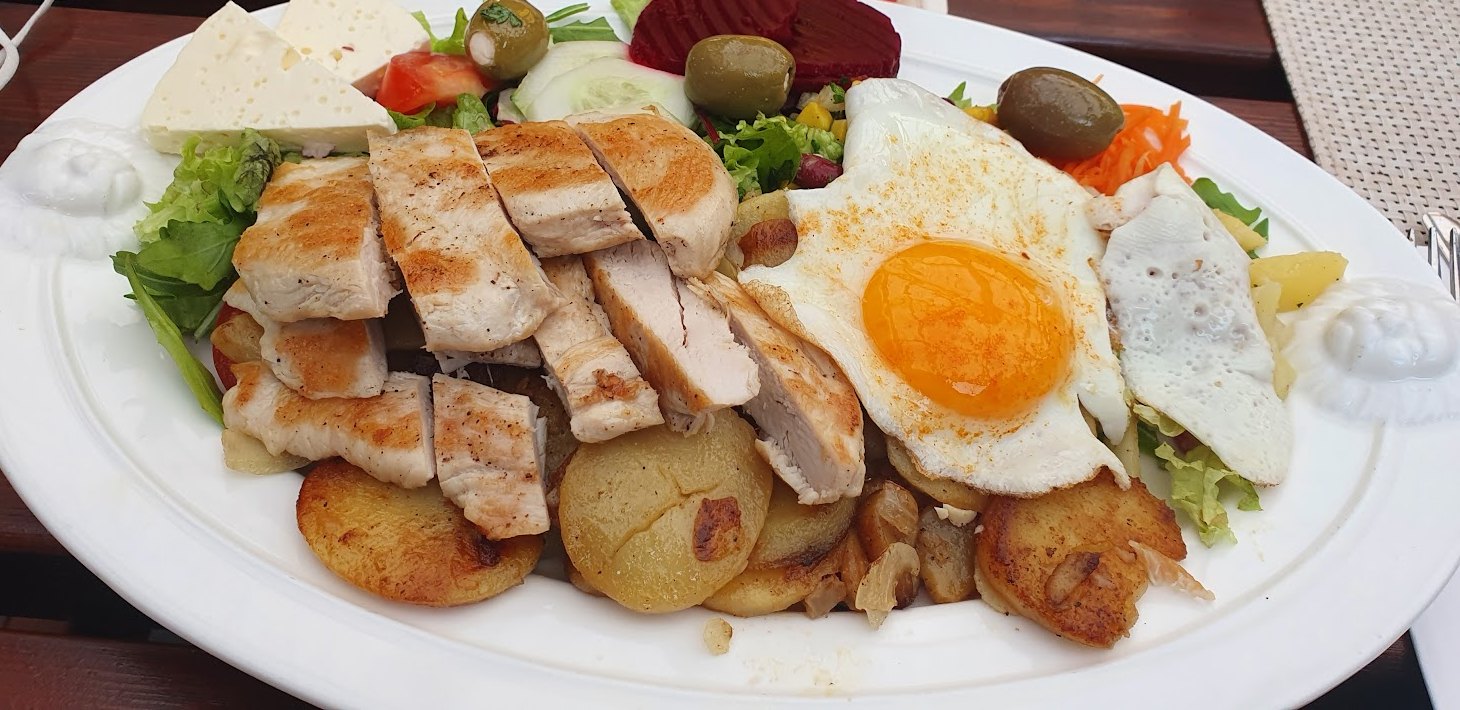 Gegrillte Hähnchenbrust mit Spiegelei, Bratkartoffeln, Salat, Schafskäse und Oliven