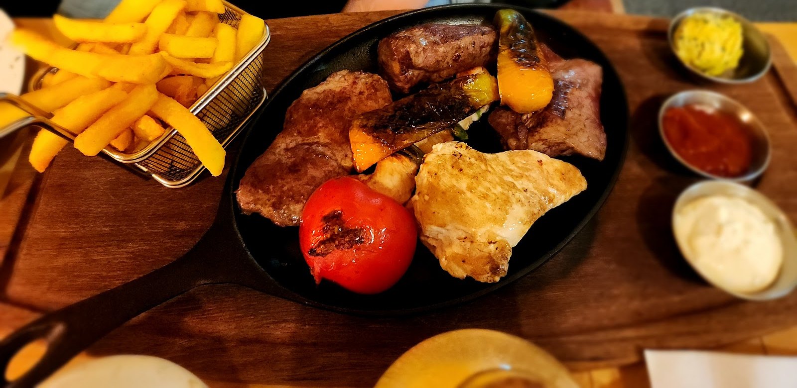 Grillpfanne mit Steak, Hähnchen, gegrillter Tomate und Paprika, Pommes im Körbchen