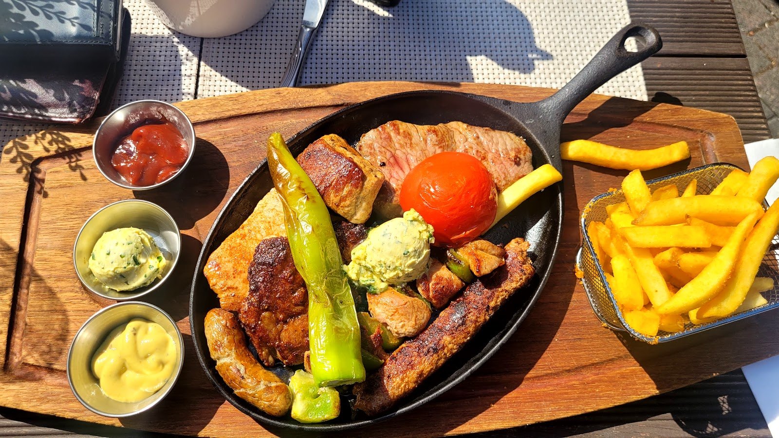 Gemischte Grillpfanne mit gegrillter Peperoni, Tomate, Kräuterbutter, Pommes und drei Dips