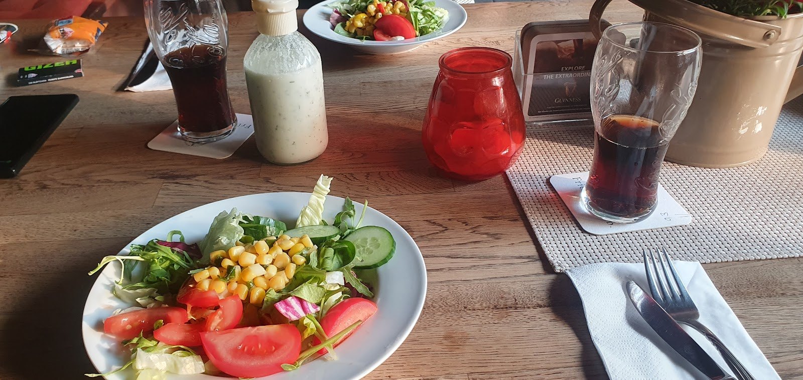 Gemischter Salat mit Mais auf dem gedeckten Tisch, daneben Getränke