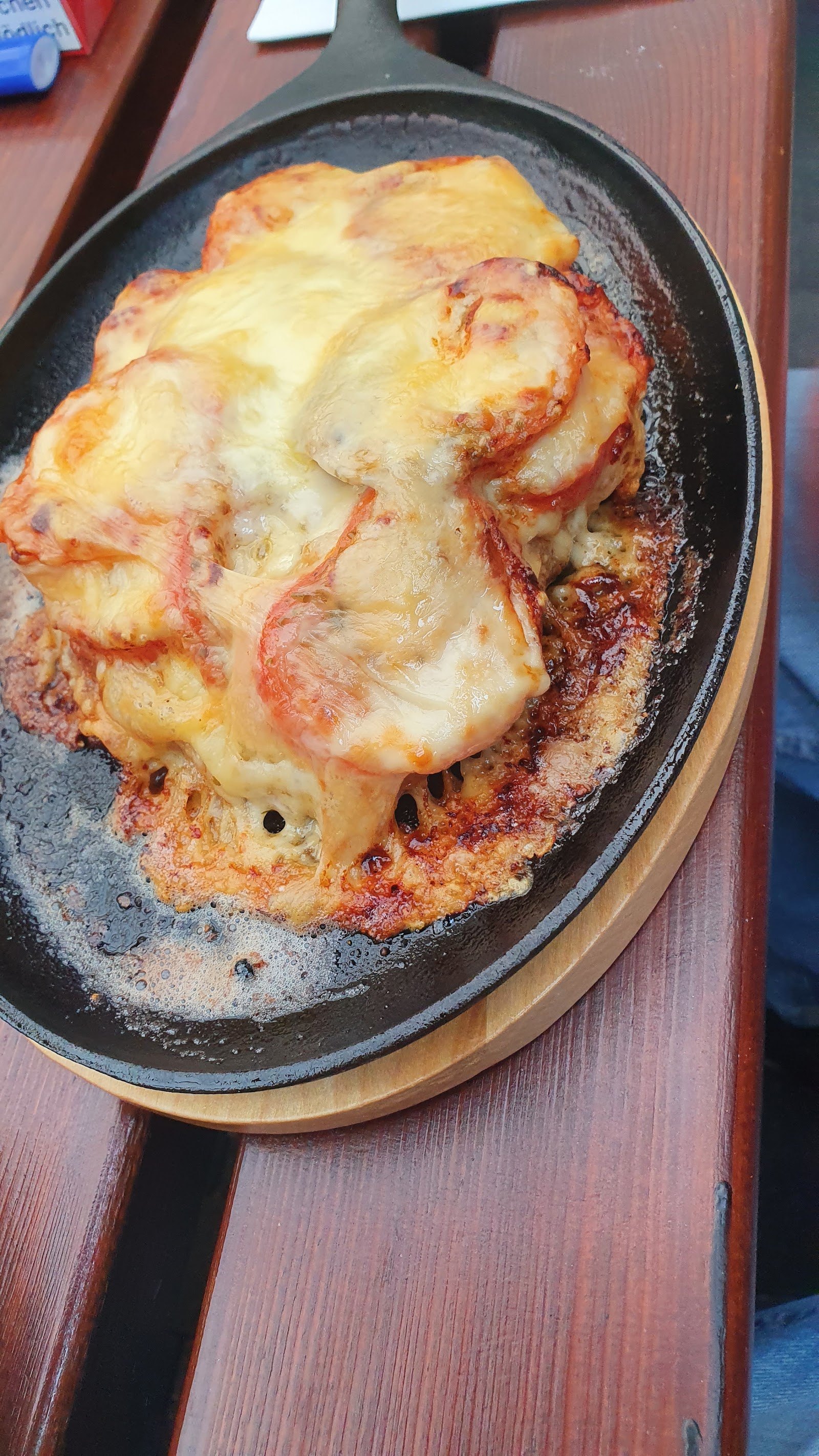 Mit Tomaten und Käse überbackenes Gericht in der gusseisernen Pfanne